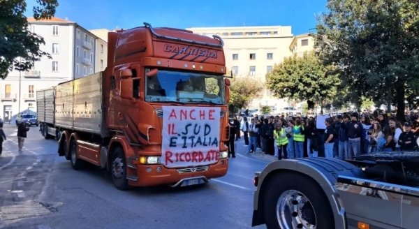 Truck participating in a transport strike demonstration in southern Italy, with protesters gathered alongside the road.