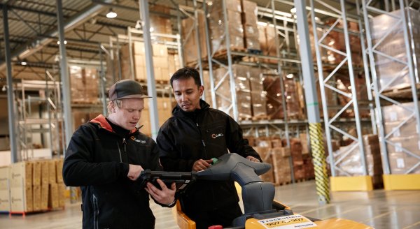Due dipendenti in divisa che conversano nel magazzino circondati da merci