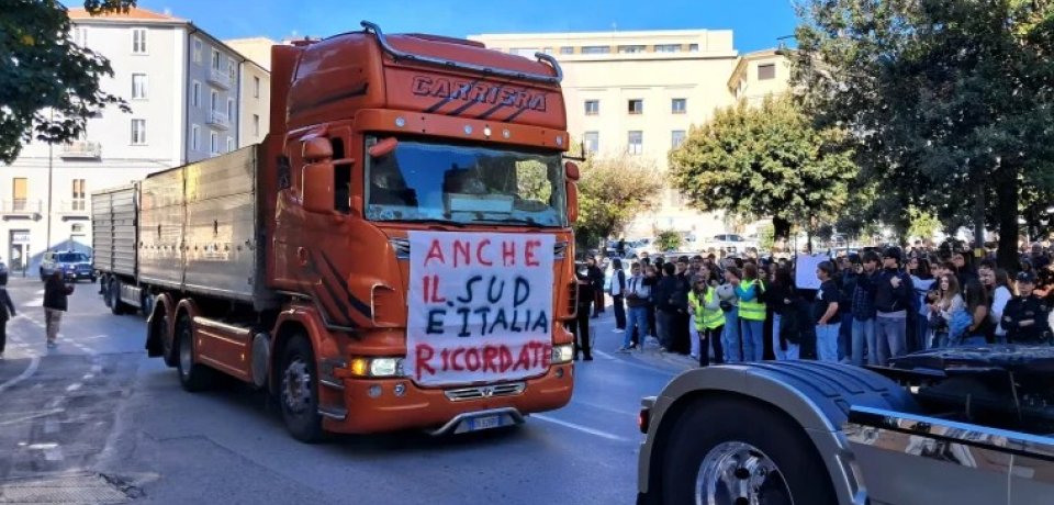 Truck participating in a transport strike demonstration in southern Italy, with protesters gathered alongside the road.